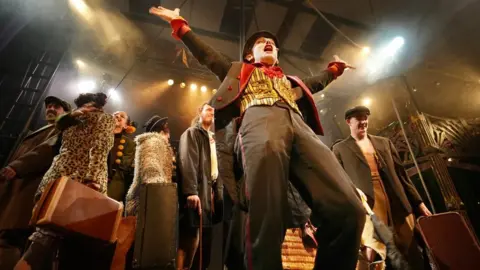 Colin Moody/ Plaster Co-founder Doug Francis in costume performing with a group on stage