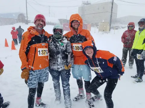 Sadie Rusby Justin Rowlatt (left) and cameraman Ben Sadd pose with the masked organiser of a 10K run, and David Vaughan (right)