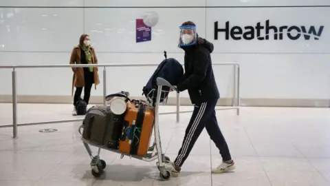 Getty Images Passenger in face mask in airport arrivals hall