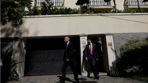 Reuters Two men are seen leading way out of Mr Nuzman's address after warrants were issued