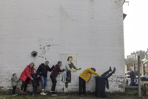 Dan Kitwood / Getty Images A family do the conga next to a new artwork called Valentine's Day mascara in Margate, Kent, 15 February 2023