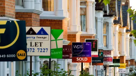 Getty Images Row of houses with For Sale, Sold and To Let signs in front of them 