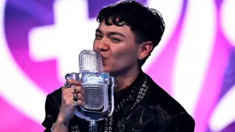 Austrian singer JJ smiles as he kisses the Eurovision Song Contest trophy.
