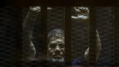 AFP Ousted Egyptian president Mohamed Morsi gestures from the defendants cage as he attends his trial at the police academy on the outskirts of the capital Cairo
