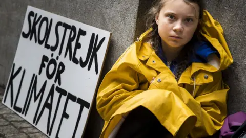 Getty Images Greta Thunberg sits next to her school strike for climate sign