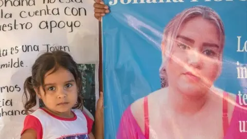 NATALIA ALBERTO A girl stands next to the placard asking for the release of Johana Flores