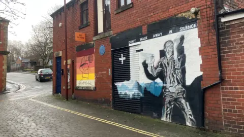 Photograph of the former Cargo Studios on Kenion Street in Rochdale. The image shows a mural of the Joy Division frontman Ian Curtis.