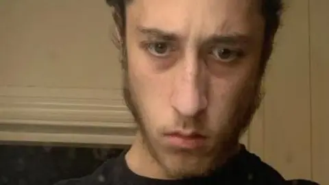 Met Police Alfie Coleman looking serious and frowning in a selfie. The top of his head is out of vision, but the side of his brown hair and sideburns are pictured.