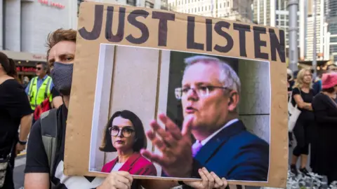 Getty Images A protester holds up a sign urging Prime Minister Scott Morrison to listen to women's accounts