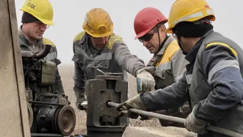 Moose Campbell Four men in hard hats working