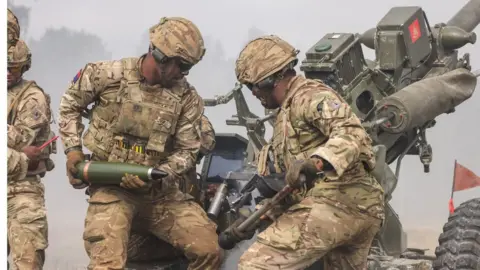 UK MOD/Crown copyright Soldiers load shells into an artillery piece in Estonia