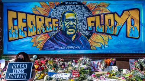 Getty Images Flowers, signs and balloons are left near a makeshift memorial to George Floyd near the spot where he died while in custody of the Minneapolis police, on May 29, 2020 in Minneapolis, Minnesota