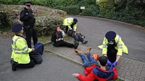 PA Media Protesters from Insulate Britain are arrested by police in the car park of the DoubleTree Hilton