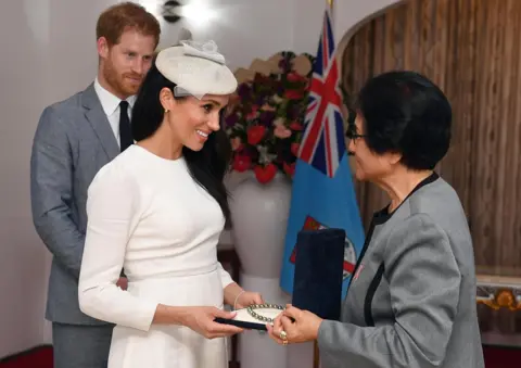 Getty Images Meghan, Duchess of Sussex is presented with a pearl necklace from Sarote Faga Konrote as Prince Harry, Duke of Sussex looks on during the first day off their tour to Fiji on October 23, 2018 in Suva, Fiji