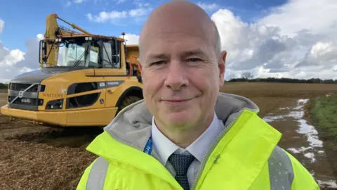 Nick Harris Nick Harris standing next to a digger and wearing a high vis jacket