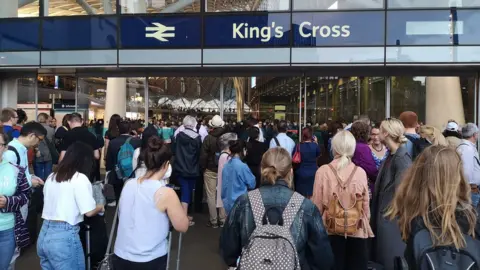 PA Media Passengers queuing after a power cut at King's Cross station