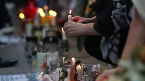 PA A candle being laid at a tribute