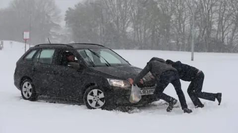 PA Two men push to help a driver try to get his car moving