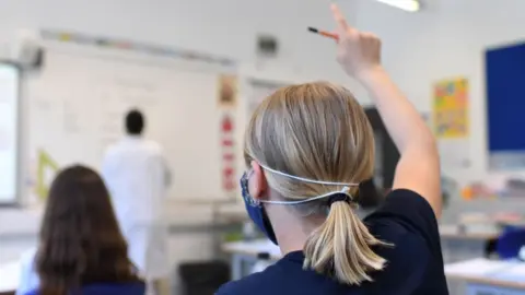 Getty Images A pupil raises her hand at a school in England