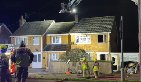 Leicester Media Online Two houses. The one on the right has windows open and four firefighters stood outside.