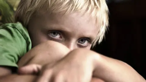 Getty Images A file photo of a blonde boy with blue eyes cowering