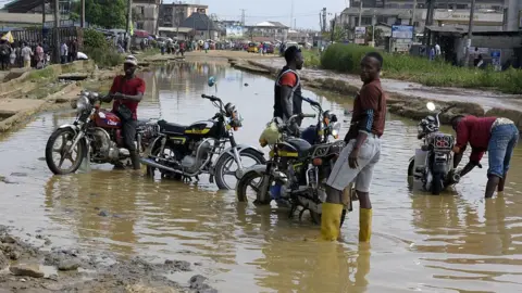 AFP Motorcyclists wash their bikes in the flooded and dilapidated Port Harcourt-Aba highway abandoned by maintenance agencies resulting in an ongoing pro-Biafra protesters agitating for the breakaway of a Biafran state, on November 18, 2015