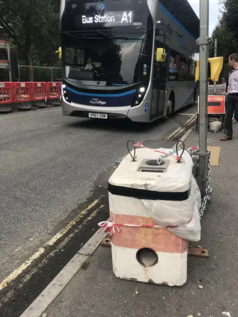 The concrete block with a possible Banksy on it, covered with a plastic sheet