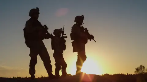 Getty Images The silhouette of three soldiers