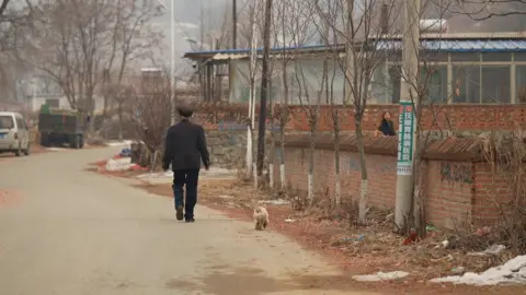 Xiqing Wang/ BBC Mr Cao walking down the street