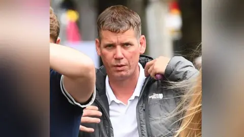 Wales News Service A man with dark hair, wearing a black jacket and white shirt