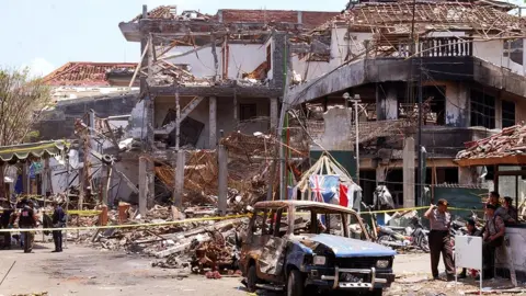 Getty Images The aftermath of the Bali bombing, showing the damaged building and a burnt-out car.