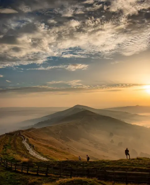 Daniel Shepherd People walking along a hill path at sunset