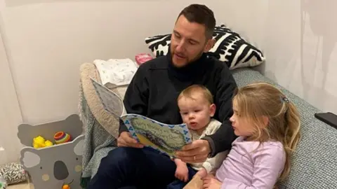 Gray Family Adam reading a book to his two children