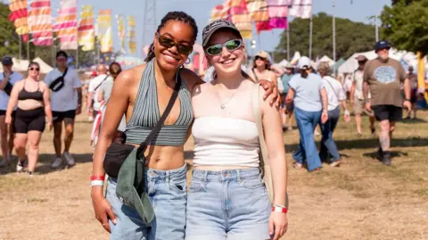 PA/IOW FESTIVAL Two female festival-goers enjoy the sunshine at the Isle of Wight Festival.