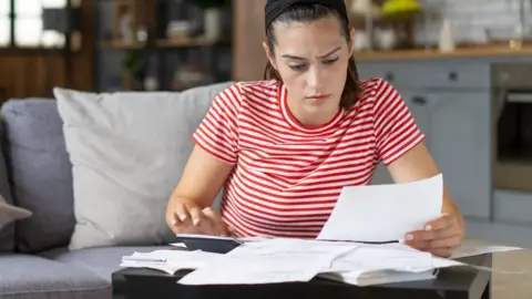 Getty Images Woman looks at bills