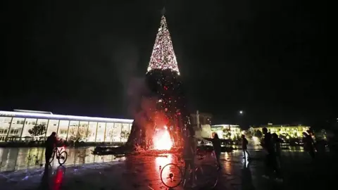 Image shows protesters setting fire to Christmas tree