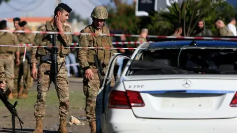 EPA Lebanese soldiers inspecting a wrecked car following a drone strike on Saturday