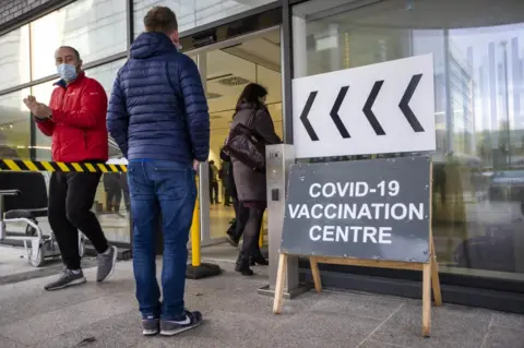 PA Media People in queue outside a Covid-19 vaccinaton and booster clinic