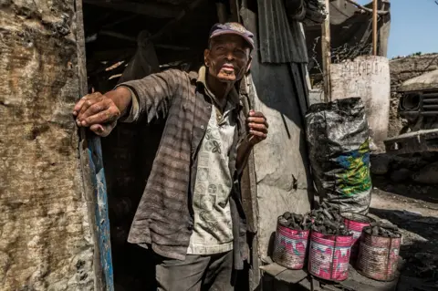 Tariq Zaidi Loreu stands at the entrance to his charcoal shop