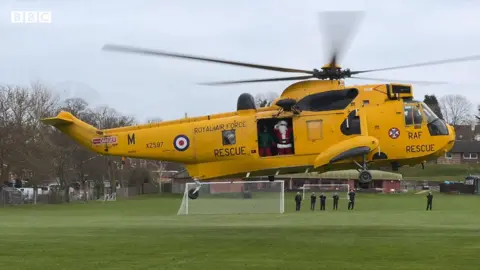 Santa waves from a Sea King helicopter