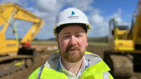 Mike Goddard in a yellow jacket and white hard hat