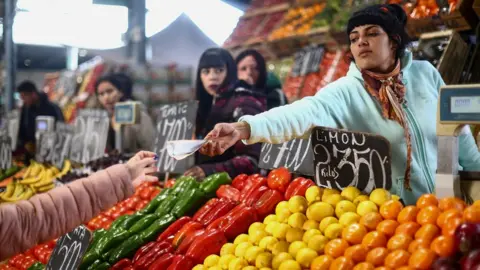 Reuters A saleswoman gives change to a customer at a greengrocer's shop in Buenos Aires