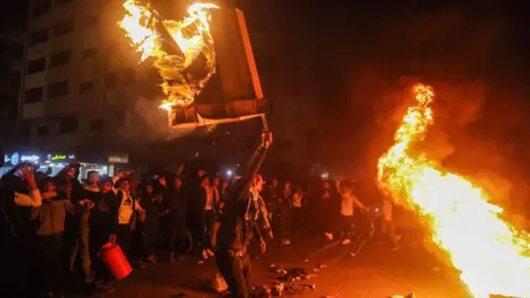 Getty Images Palestinians burn tires and celebrate in Gaza City after a Palestinian gunman opened fire outside an East Jerusalem synagogue