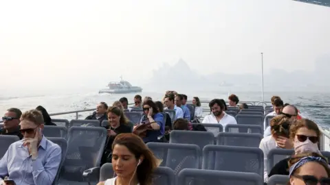 Getty Images Passengers on a ferry on Sydney Harbour during a smoke haze across the city which has almost obscured the Sydney Opera House in the background