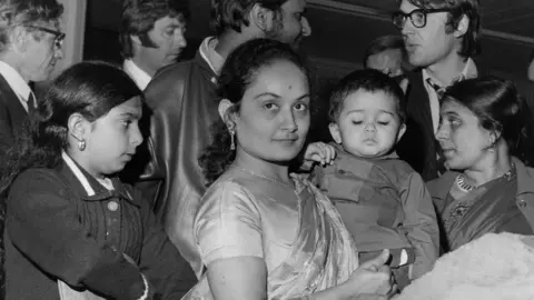 Getty Images Asian women, one holding a child, arrive in London after the forced expulsion of minorities from Uganda