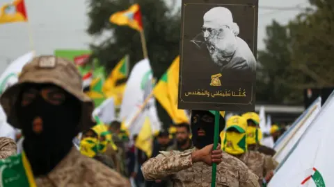 AFP Kataib Hezbollah militia fighters hold up a poster showing Qasem Soleimani and Abu Mahdi al-Muhandis at their funeral in Baghdad (4 January 2019_