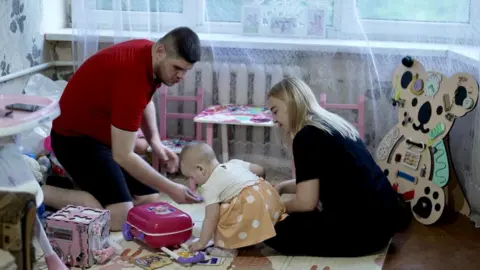 BBC/DAVY MCILVEEN Viktoria (right) with her husband Serhiy and their daughter Eva