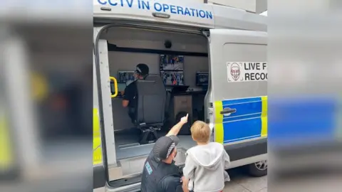 Essex Police A police officer points inside a van as he shows a boy the technology behind the facial recognition cameras