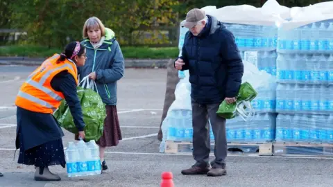 PA Media Residents collecting water from a bottled water station