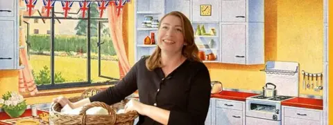 Alena with basket in front of illustrated kitchen